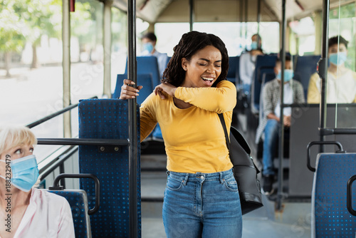 Photography Black lady sneezing and coughing in elbow standing inside public transport witho