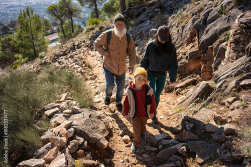 Obraz na plátně Senior grandfather hiking with grandson and boy’s mother on rocky mountain trail