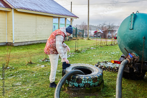 Pumping sewage from septic tank using vacuum truck hose as worker controls suction process and ensures complete removal of liquid waste.