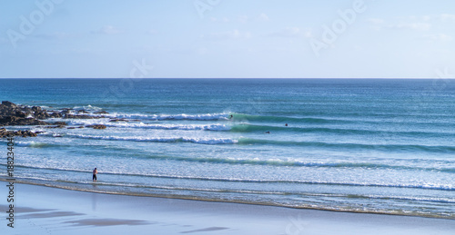 Photography Forestry beach in Auckland, New Zealand with people surfing on beautiful waves and lovely blue water