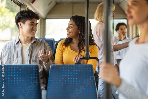 Obraz na plátně Portrait of happy cheerful couple sitting on city bus seat, young black lady and