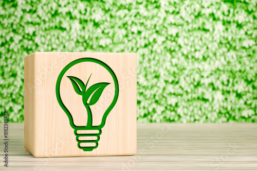 Wooden block with light bulb and plant icon on green leaf background sustainability concept