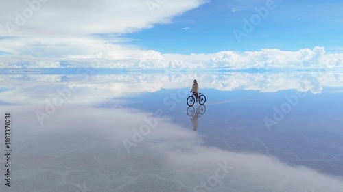 A woman cycling across the expansive Salar de Uyuni salt flats in Bolivia, capturing the surreal beauty of the reflected sky