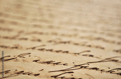 Extreme closeup of old handwritten manuscript on yellowed paper with cursive ink writing, shallow depth of field soft blurred background, vintage document texture history, literature, poetry, archival