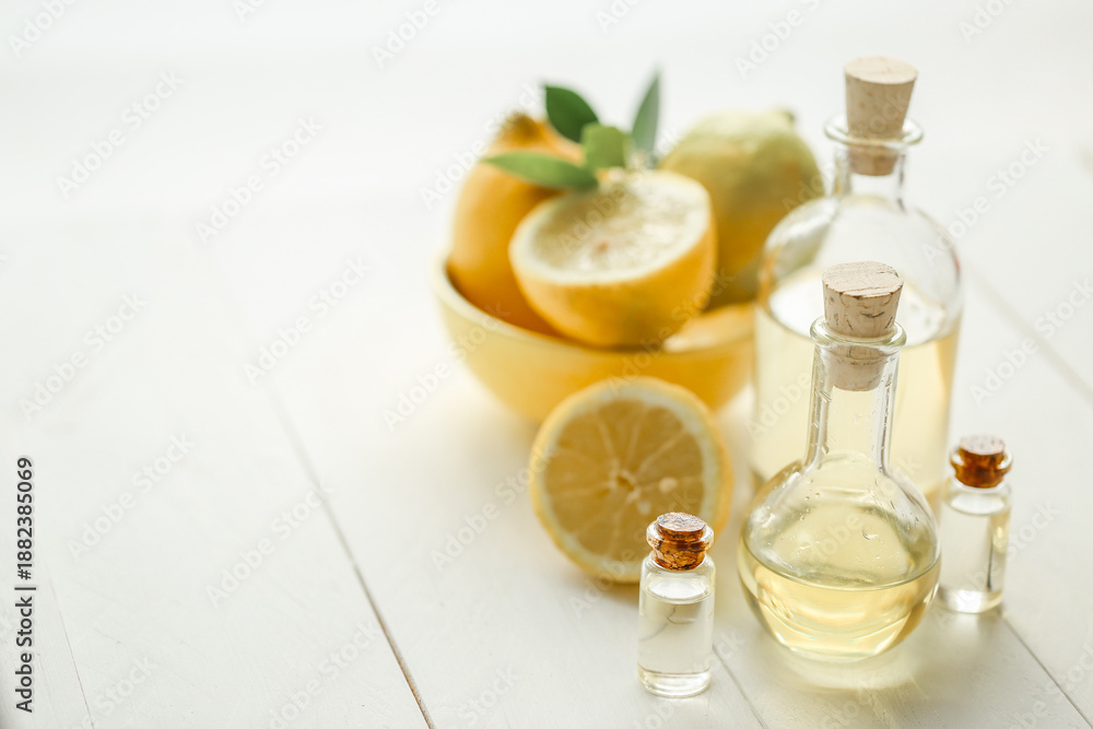 Fototapeta premium Natural lemon oil in glass bottle with cork stopper and fresh lemons. Concept of organic skincare, cosmetic ingredients and healthy living.