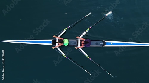 Top View Four young athletes row together in an eight-oar boat during sunrise training. Serene ocean and warm morning light frame focused preparation for rowing competition.