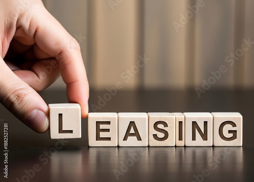 Man puts cubes with the word 'Leasing'. Property, buildings and vehicles are common assets. A lease is a contractual arrangement calling for the lessee to pay the lessor for use of an asset. concept. 