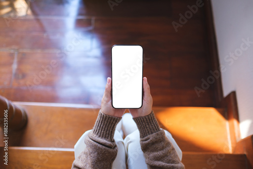 Wallpaper Mural Top view mockup image of a woman holding mobile phone with blank desktop screen while sitting on wooden stairs at home Torontodigital.ca