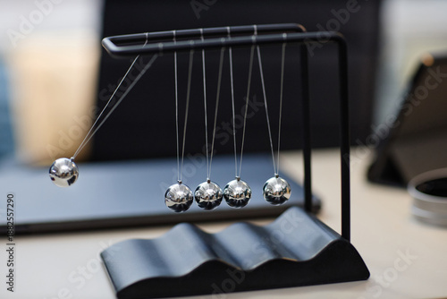 Quadro su tela Newton cradle swinging on desk, five metal spheres suspended in motion, demonstr