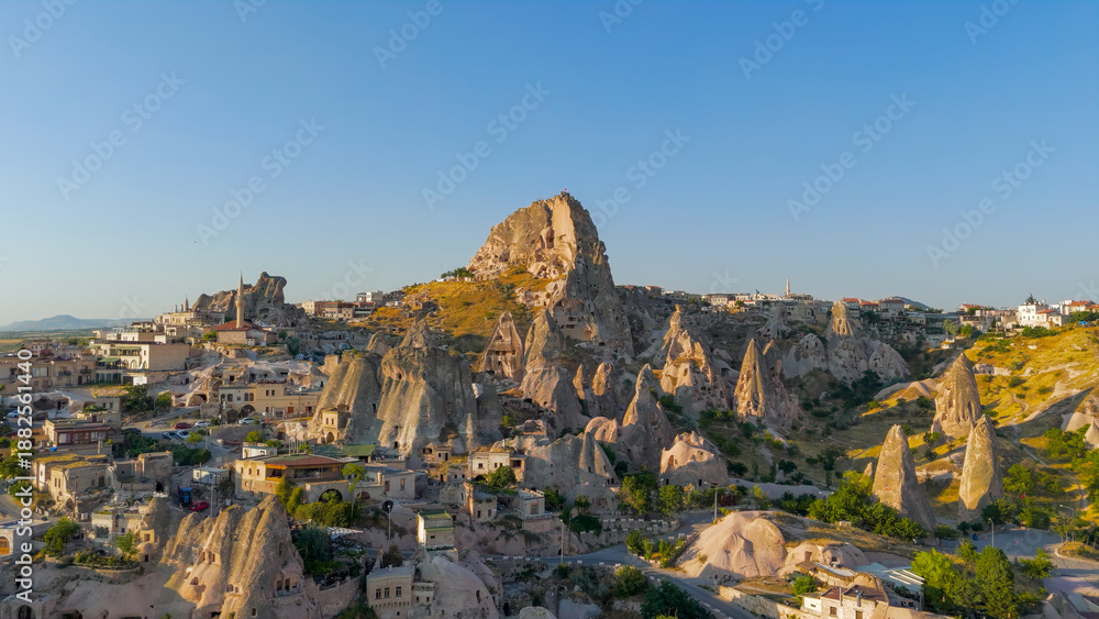 Obraz premium Uchisar, Nevsehir, Turkey - July 13, 2025: Aerial view blending ancient Uchisar Castle with modern Uchisar town and tourist facilities.. Aerial View