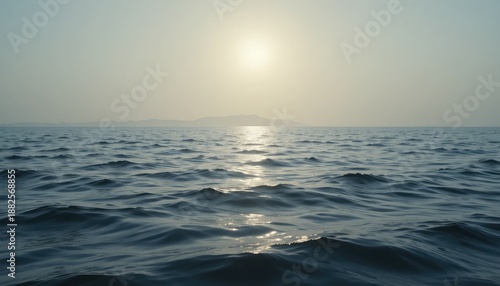 Ocean waves under hazy sun with distant island silhouette