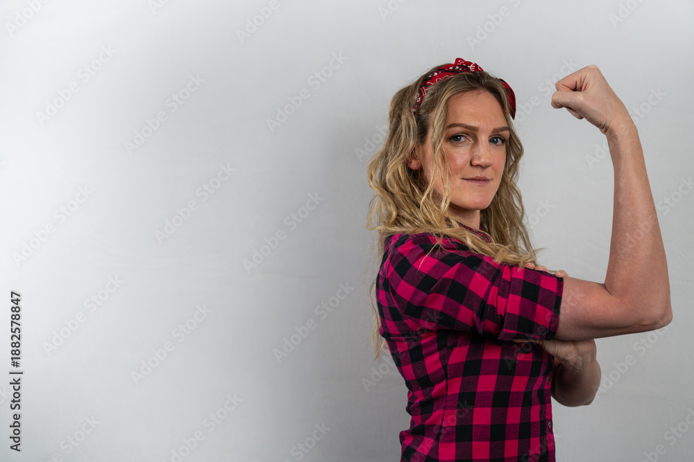 Naklejka premium Blonde woman showing her arm in a representation of power and empowerment.