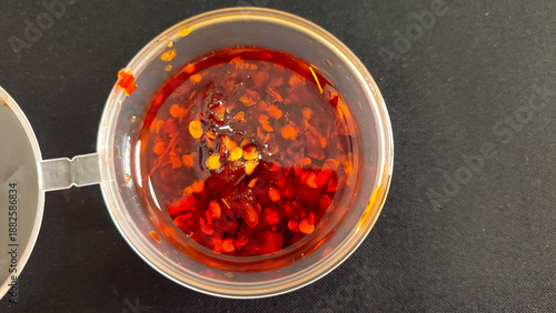 Obraz na plátně Close-up of spicy chili oil with red pepper flakes in a clear plastic container