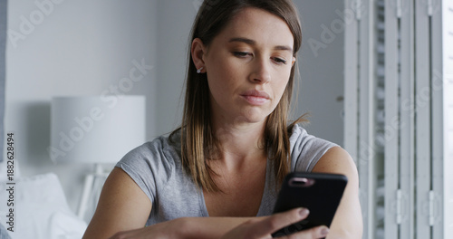Fotografie Woman, phone and sad in bedroom with texting, notification and online dating chat at apartment