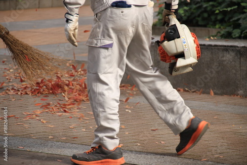 公園で紅葉した落ち葉の清掃をする人(横長)