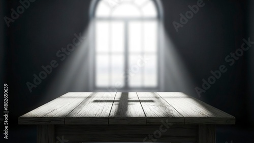 A wooden table with a cross shadow illuminated by a bright window in a dark room
