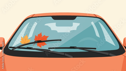 An orange car windshield with two autumn leaves and wipers