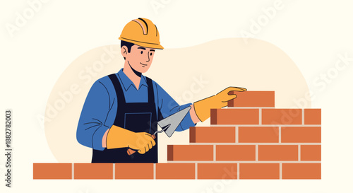 Construction worker wearing a yellow hard hat and blue overalls carefully laying bricks to build a solid wall with a metal trowel.