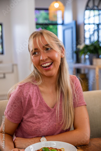 Free Download Woman sitting at cafe table smiling and looking left beside bowl of spaghetti - GFXLoad