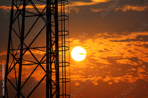 steel structure communication pole on sunset nature background . silhouette iron object mobile pole against sun dawn abstract orange sky