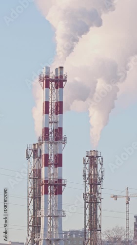 Thermal power plant pipes with vapor rising to the sky. Large vapor rising in front of the blue sunny sky.