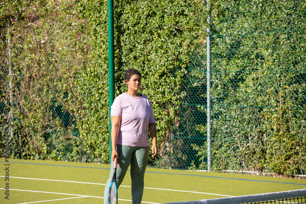 Obraz premium African american woman standing on court and holding racket in lavender shirt leggings with net