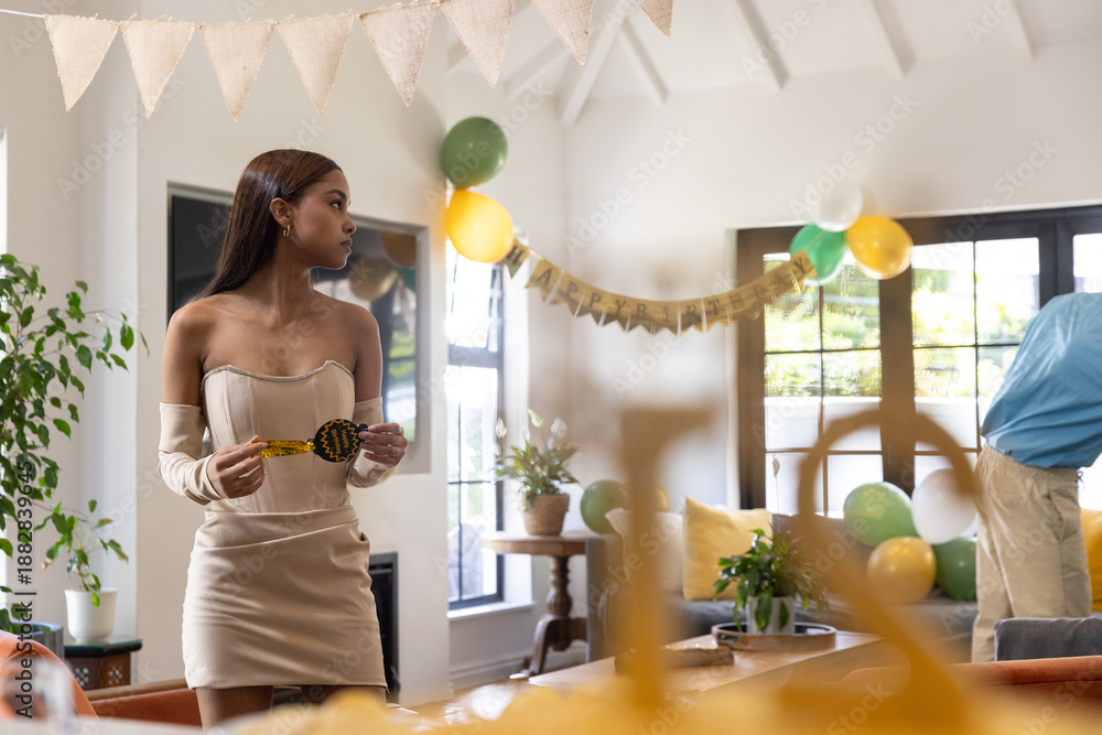 Obraz premium Diverse friends in party attire decorating living room for birthday with banner, gold decoration