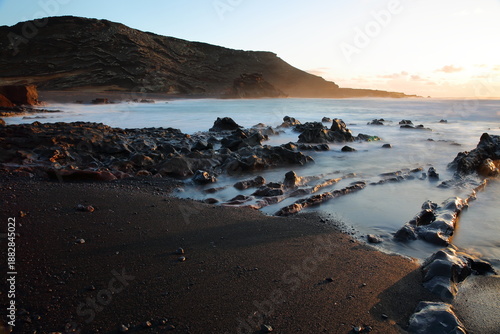 Dramatic sunset at La Cresta del Dragon Colorao, a rocky beach with crashing of waves, located next to Lago Verde (Green lake) in El Golfo, Lanzarote, Canary Islands, Spain
