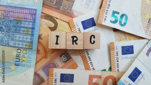 IRC acronym made of wooden letter cubes on pile of Euro banknotes. Imposto sobre o Rendimento das Pessoas Coletivas (Corporate Income Tax)