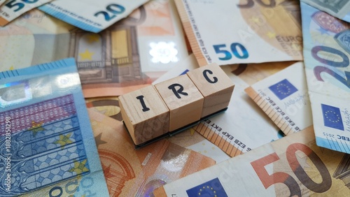 IRC acronym made of wooden letter cubes on pile of Euro banknotes. Imposto sobre o Rendimento das Pessoas Coletivas (Corporate Income Tax)