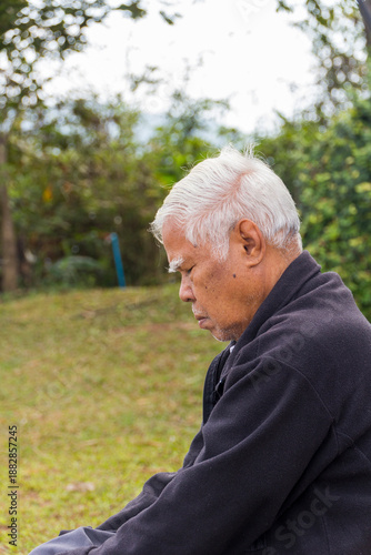 Portrait of Asian senior man sitting on the grass in the park
