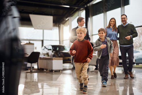 Happy boys having fun while being with their parents in auto salon.