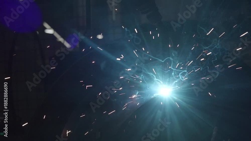 Robotic arm welding metal creating sparks and smoke