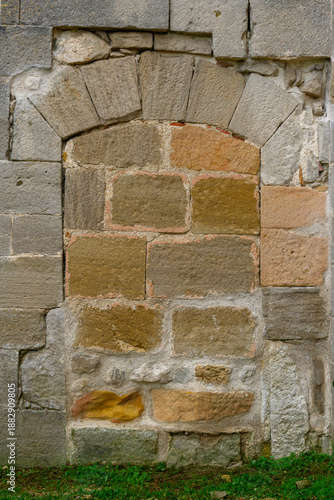 Close-up view of an old stone doorway completely sealed with sandstone blocks in a Romanesque church, showing the original carved stone frame and the infilled entrance as part of a historic architectu