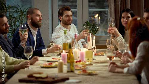 Bilde på lerret Group of friends raising wine glasses at cozy dinner table