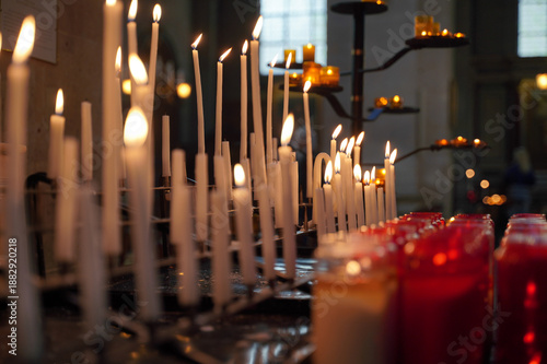Burning candles in a church create a serene and sacred atmosphere. The warm glow of candlelight enhances the tranquil setting, inviting reflection and prayer in the holy space.