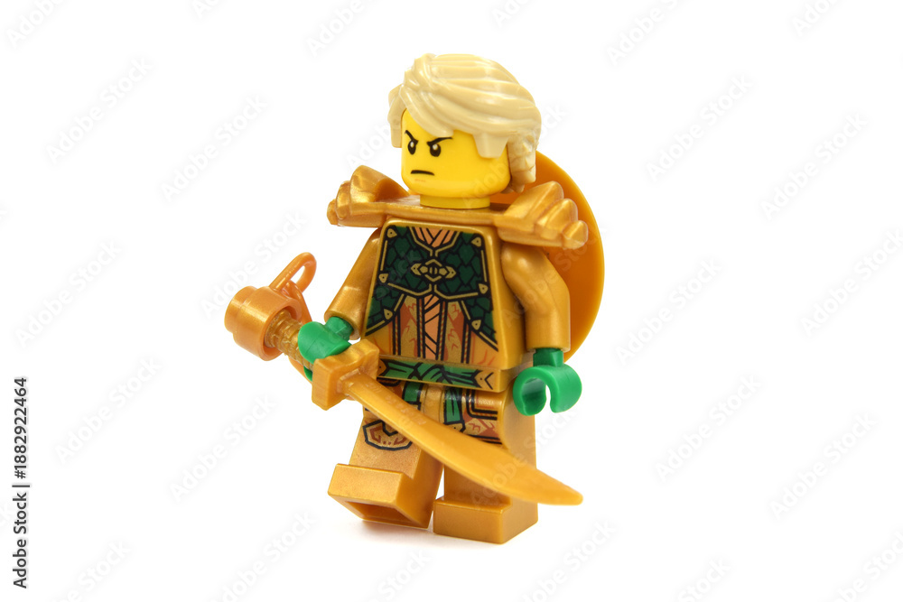 Fototapeta premium Editorial illustrative image of lego minifigure of golden ninja Lloyd with blade or sword weapon isolated on white. Jubilee of lego Ninjago.