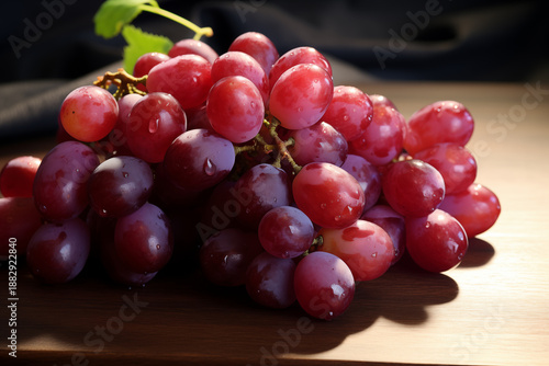 Cluster of Fresh Red Grapes with Stem on Rustic Wooden Table in Soft Daylight