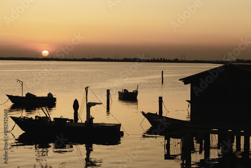 Boats backlit at sunset on the Po Delta with an atmosphere of peace and tranquility