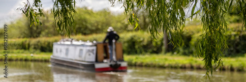 Foto Panorama of defocused narrowboat on a canal seen through the leaves of a weeping