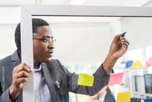 Working man writes on a glass board at work. Concept of business