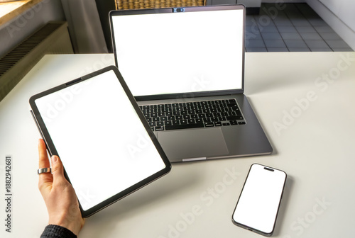 Responsive design mockup showing tablet, laptop, and mobile phone with empty screens. Clean desk setup for app or website presentation.