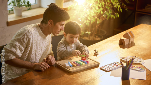 Quadro su tela Father and son playing with modeling clay at wooden table