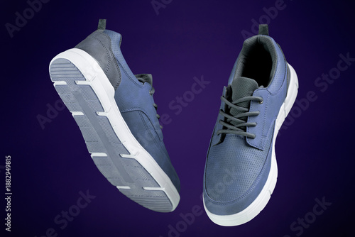 Modern blue casual sneakers floating in studio shot isolated on purple background