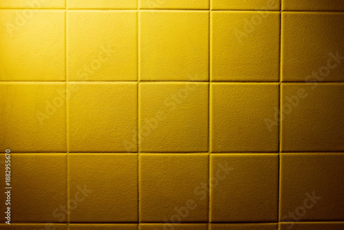фотографія Yellow padded wall panels with square grid geometry, soft fabric texture and gentle depth