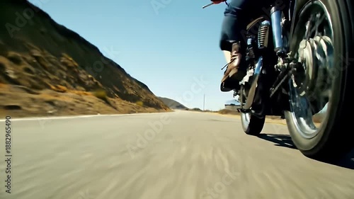 Motorcycle Rider on a Winding Road with Mountain Scenery on a Sunny Day