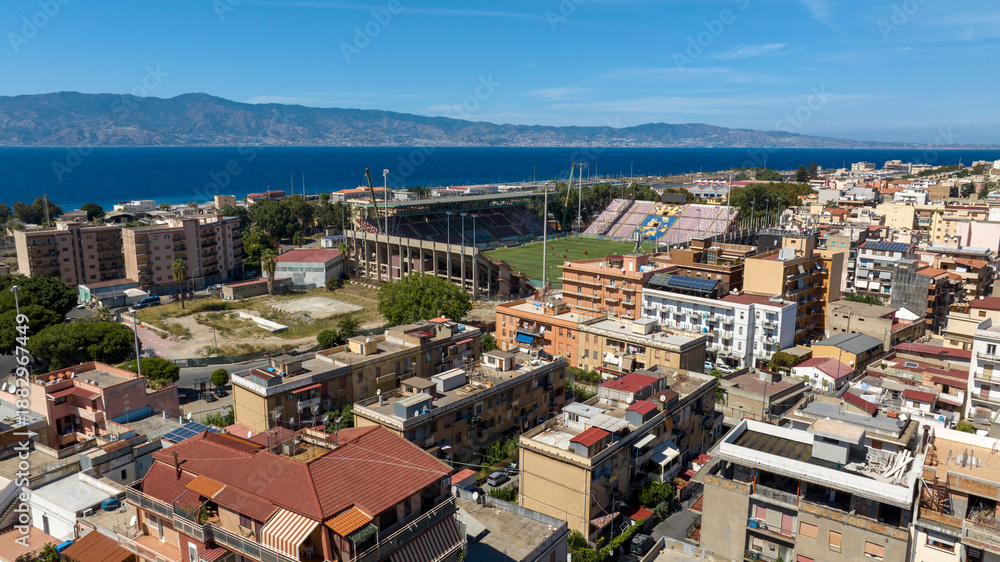 Fototapeta premium Aerial view of the football stadium located in Reggio Calabria, southern Italy. In the background, across the Strait of Messina, Sicily can be seen, separated by the sea.