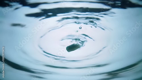 Underwater view of object falling into clear blue water creating ripples and bubbles