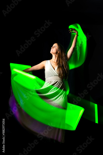 Woman creating neon green light trails, performing abstract art with motion and glow