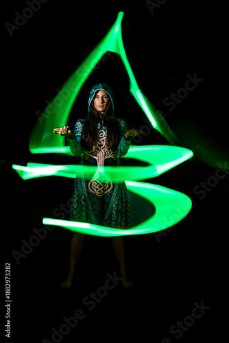 Woman creating swirling green light trails, abstract light painting art